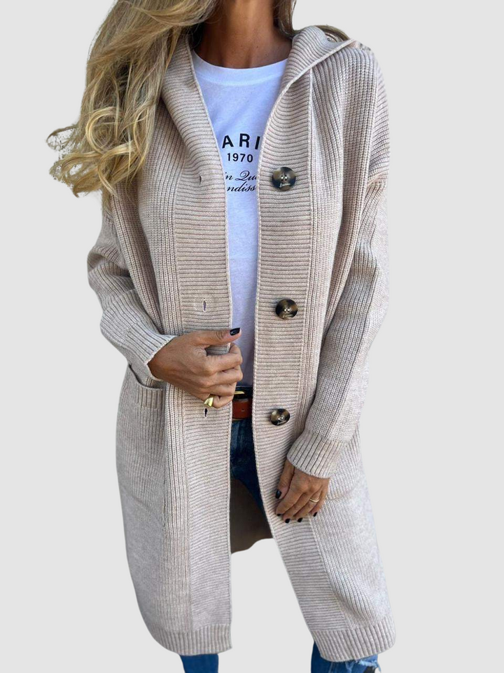 Beige knitted cardigan with large buttons and pockets, worn over a white graphic tee and jeans in studio setting.