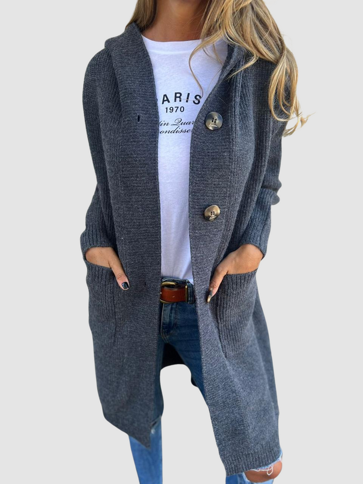 Dark grey knitted cardigan with large buttons and pockets, worn over a white graphic tee and jeans in studio setting.
