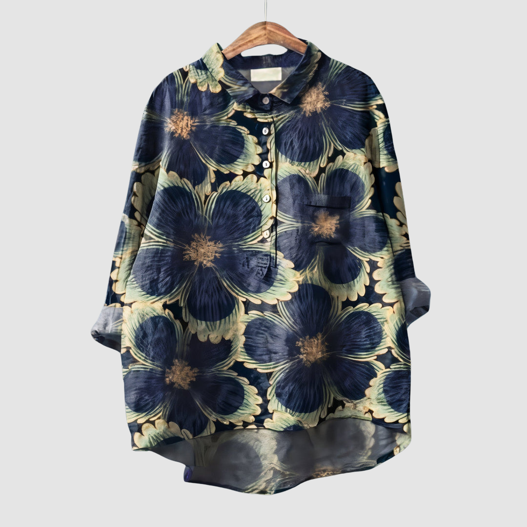 Dark floral print blouse with large blue flowers and button detail on wooden hanger against light gray background.
