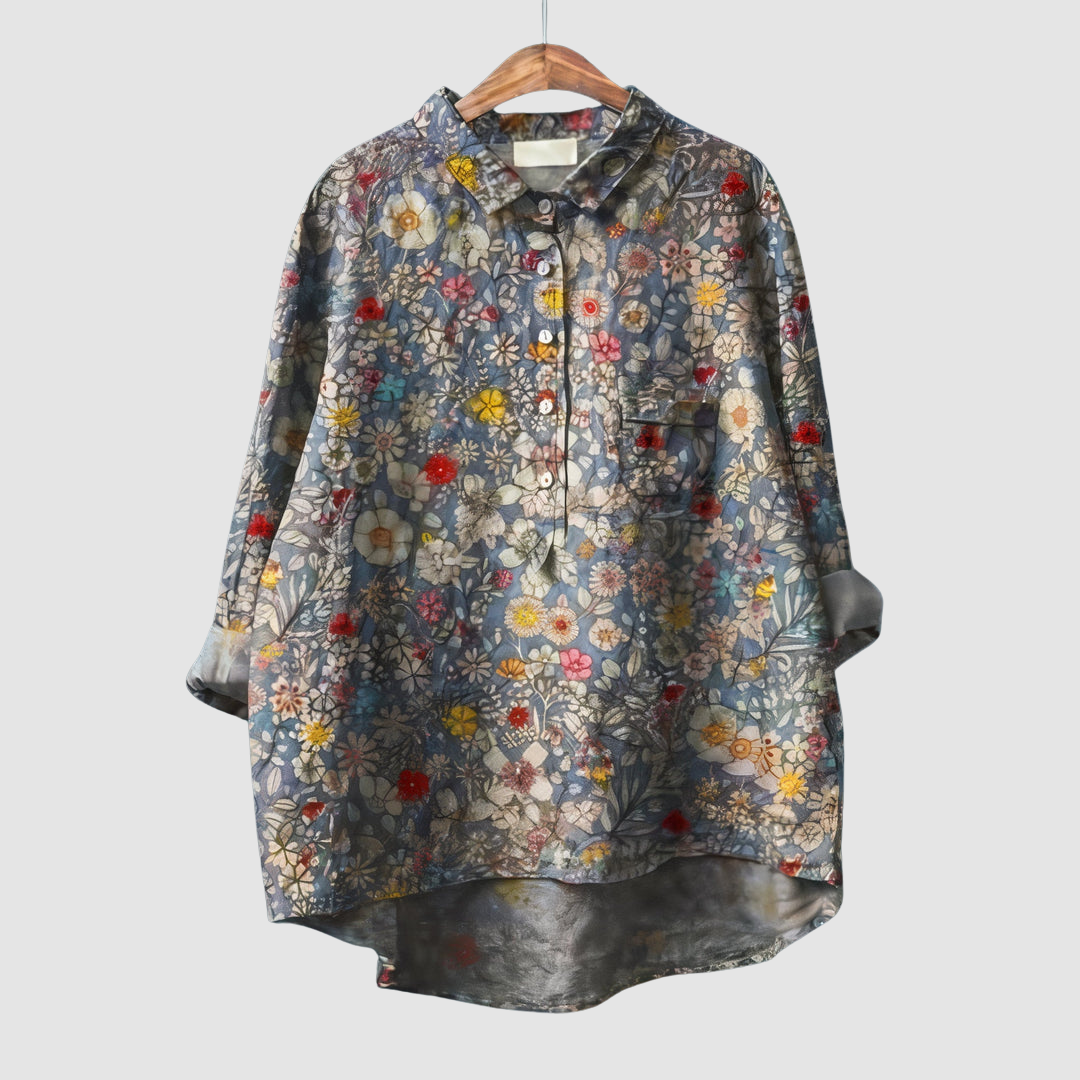 Dense floral print blouse with a mix of small flowers on wooden hanger against light gray background.