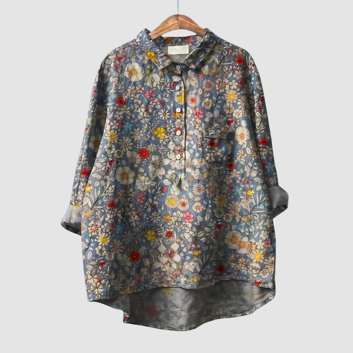Dense floral print blouse with a mix of small flowers on wooden hanger against light gray background.