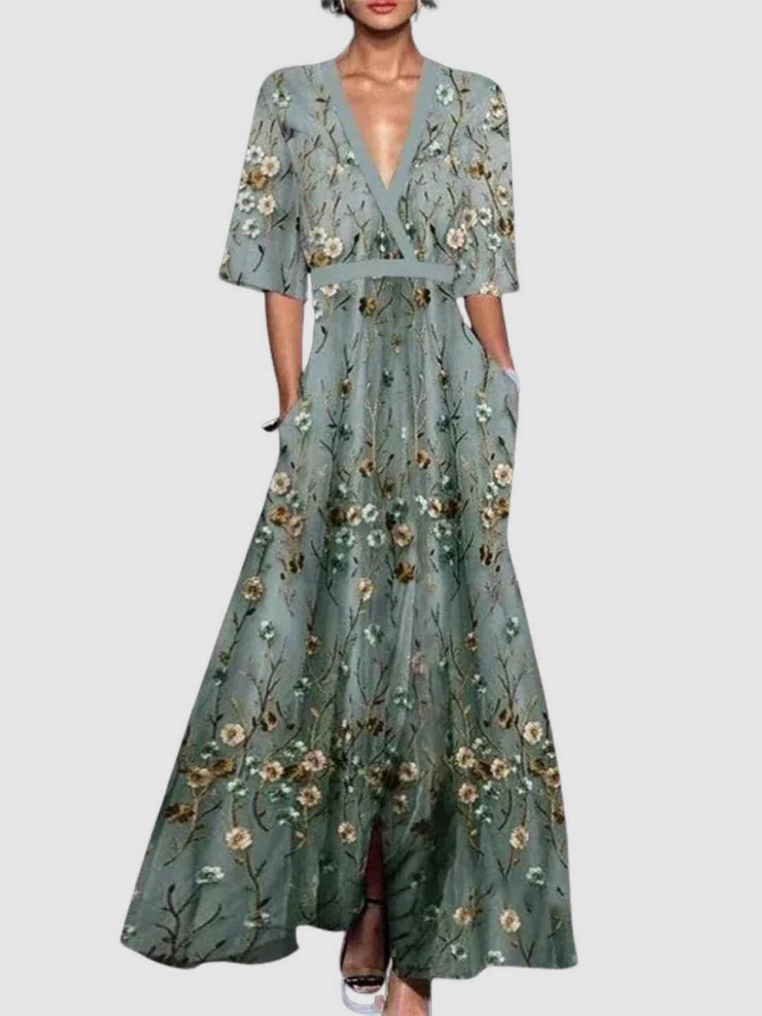Elegant long floral dress with a plunging neckline and three-quarter sleeves, featuring a flowing skirt with floral patterns, set against a plain white background.