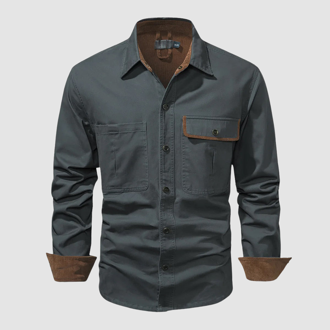 Grey long-sleeved shirt with brown inner collar and cuffs, front pocket, plain backdrop.