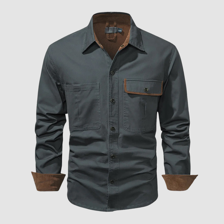Grey long-sleeved shirt with brown inner collar and cuffs, front pocket, plain backdrop.