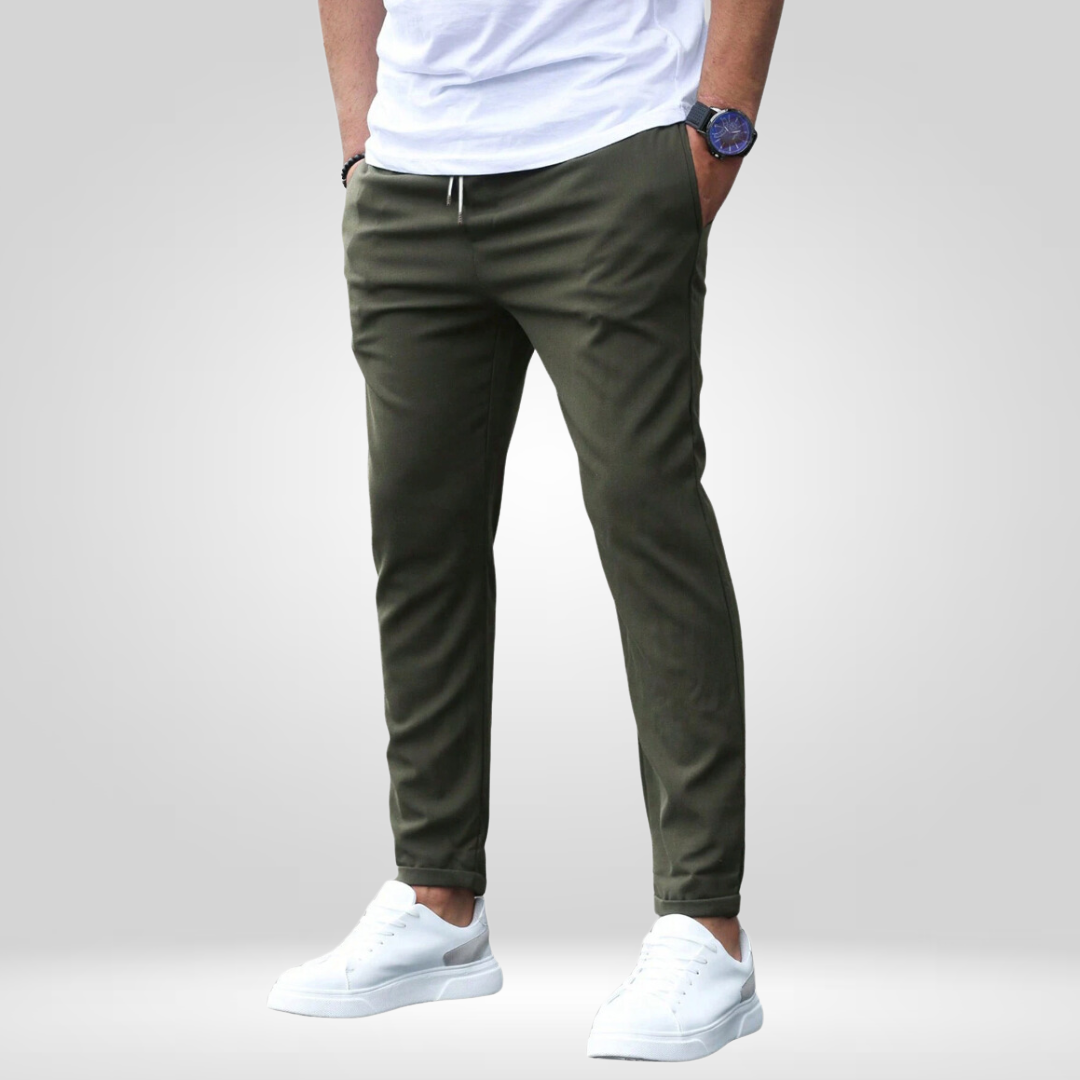 Olive stretch pants with drawstring, modeled with white t-shirt and white sneakers in a studio setting.