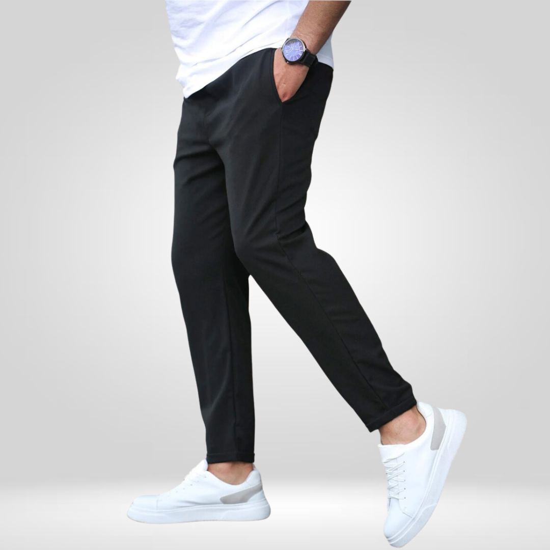 Side view of black stretch pants with white sneakers and t-shirt, displayed in a studio setting.