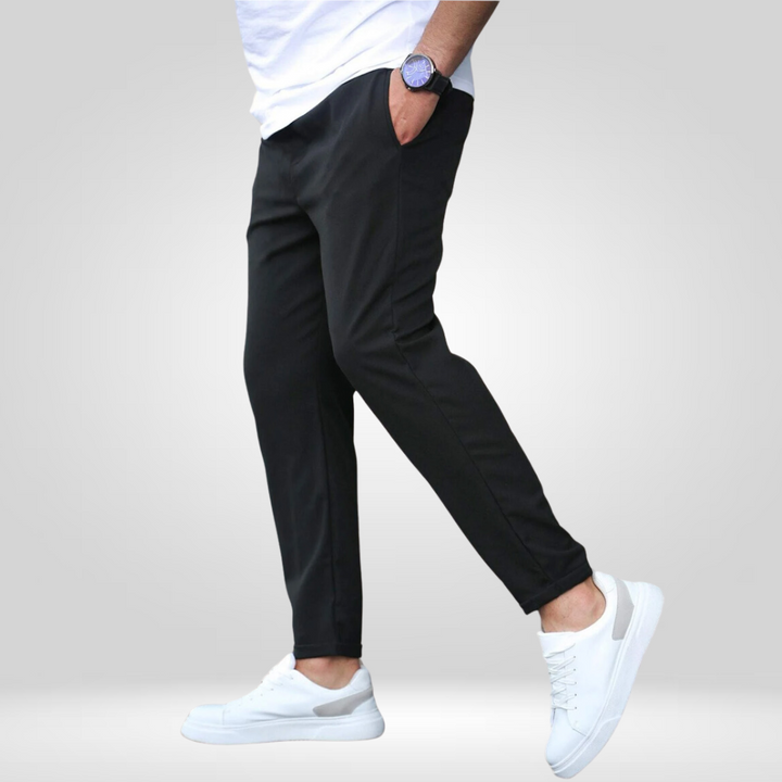 Side view of black stretch pants with white sneakers and t-shirt, displayed in a studio setting.