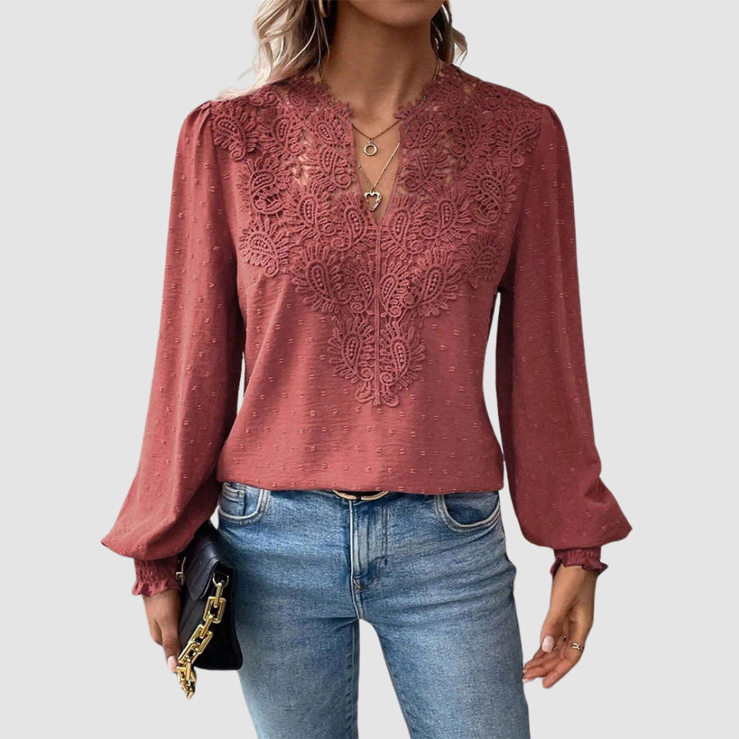 Rust V-neck lace blouse with intricate design, long sleeves, paired with blue jeans, model holding a black purse, gray background.