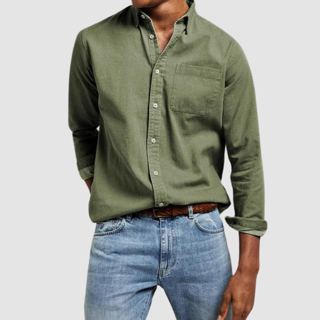 Green button-up shirt with front pocket and rolled sleeves, paired with light blue jeans against a gray background.