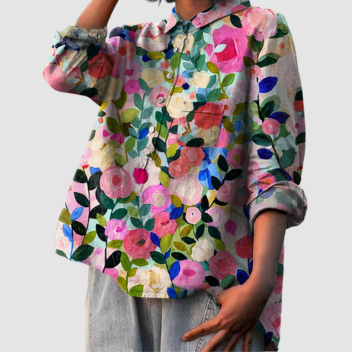 Colorful floral print blouse with rolled sleeves in a casual pose against a light gray backdrop.