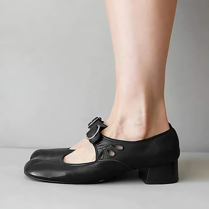 Side view of black leather sandals with buckle on feet in a neutral setting.