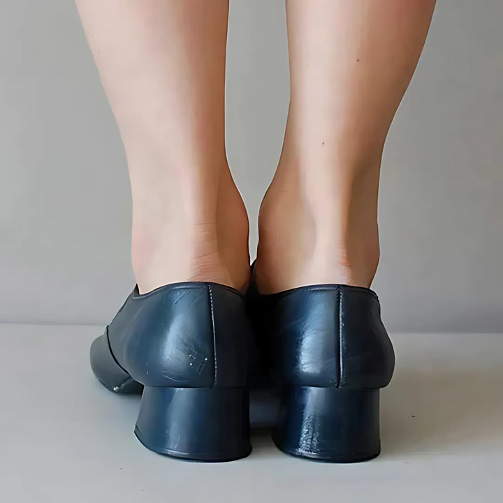 Rear view of black leather sandals on feet, highlighting heel and back design.