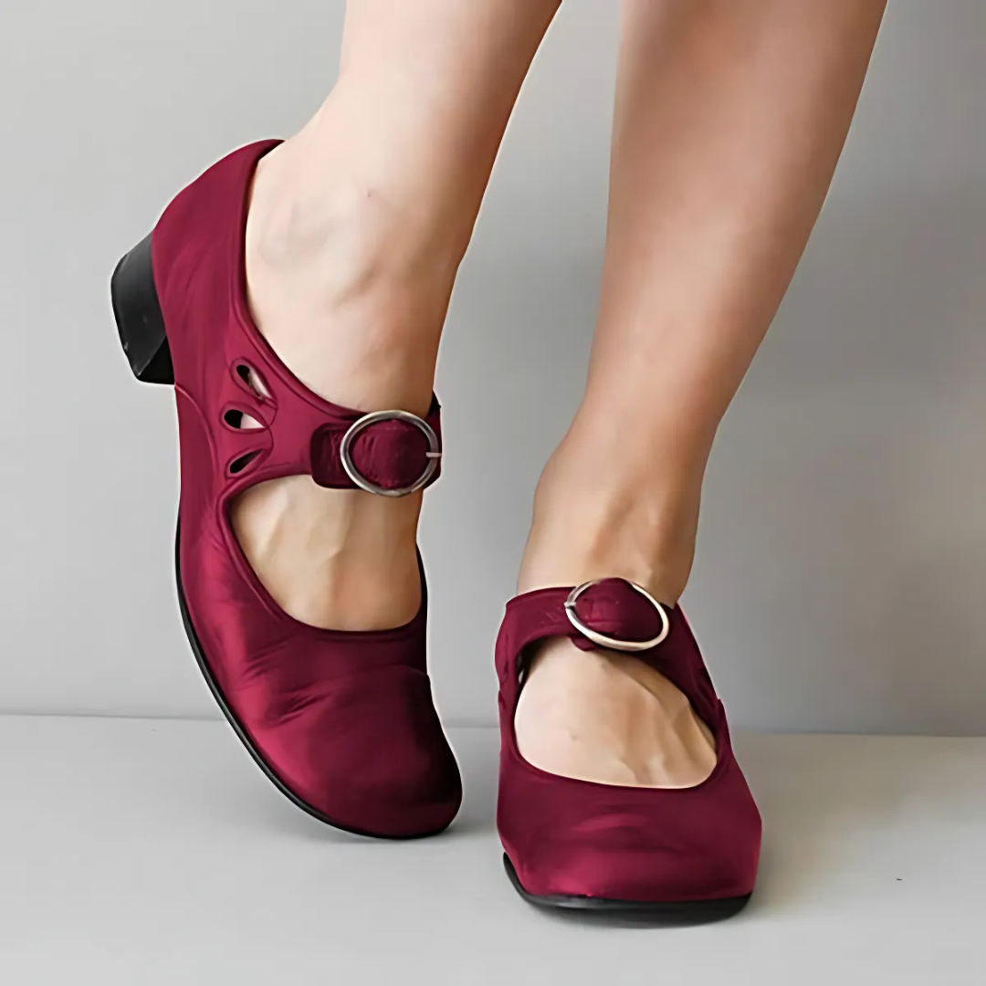 Burgundy leather sandals with buckle detail shown from the front on feet against a neutral background.