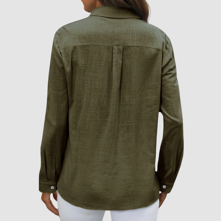 Back view of olive blouse with pleat detail and buttoned cuffs, studio setting.