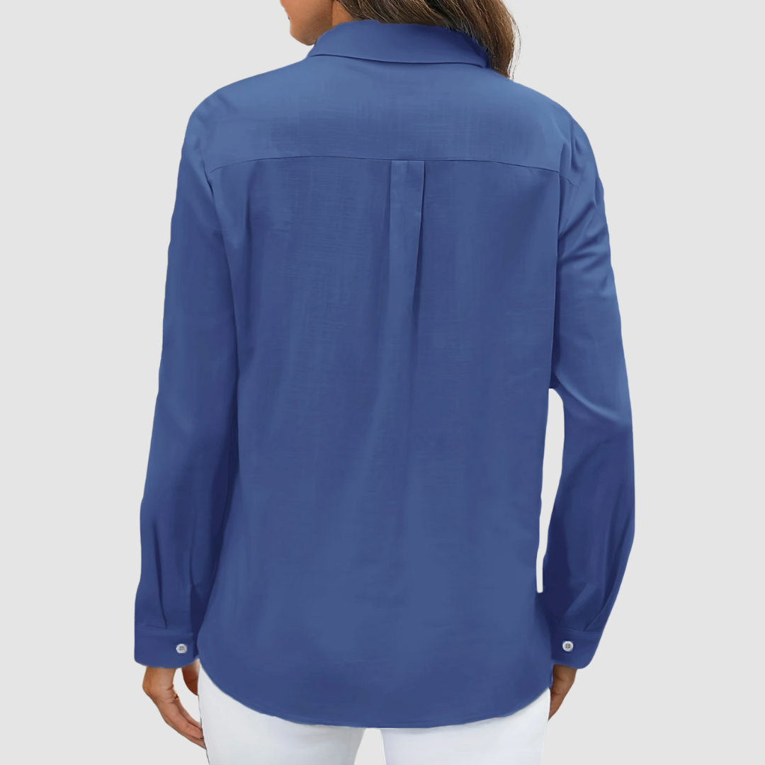 Back view of deep blue blouse with pleat detail and buttoned cuffs, studio setting.