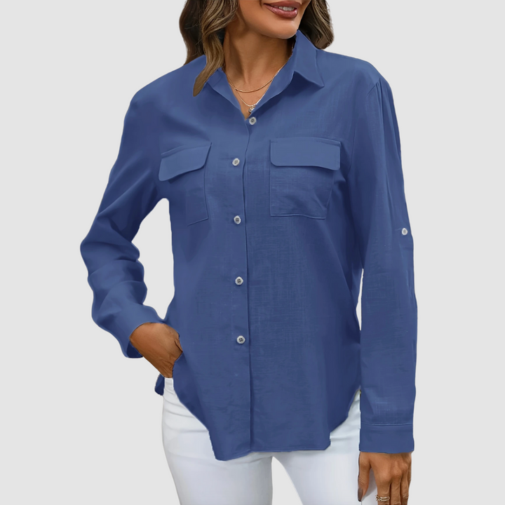 Deep blue pocket blouse with long sleeves and front pockets, hand in pocket, studio background.