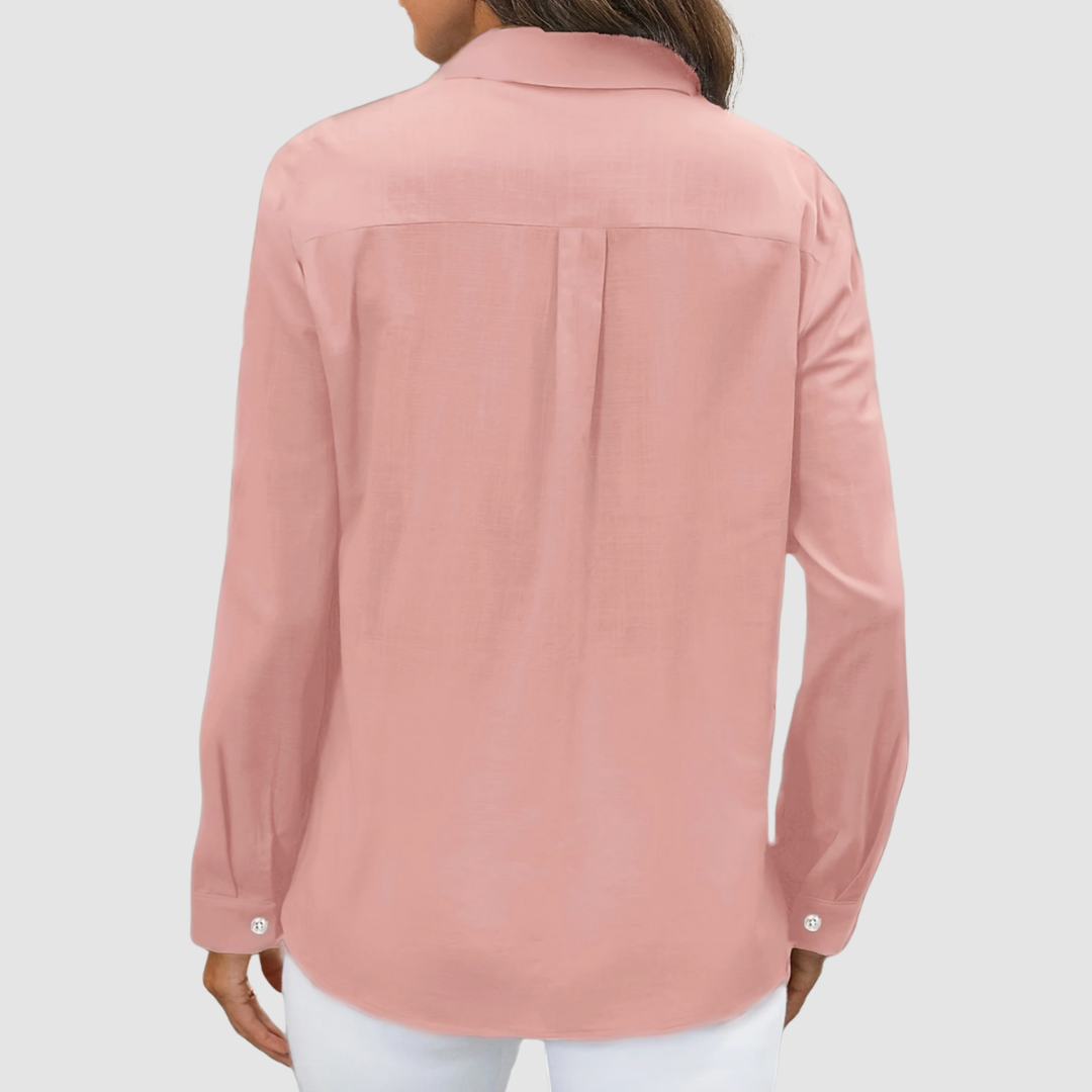 Back view of pink blouse with pleat detail and buttoned cuffs, studio setting.