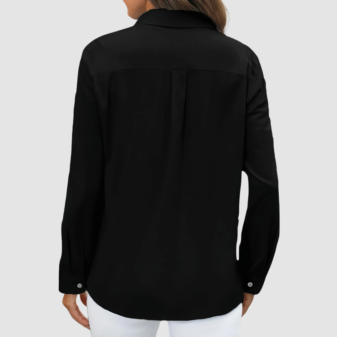 Back view of black blouse with pleat detail and buttoned cuffs, studio setting.