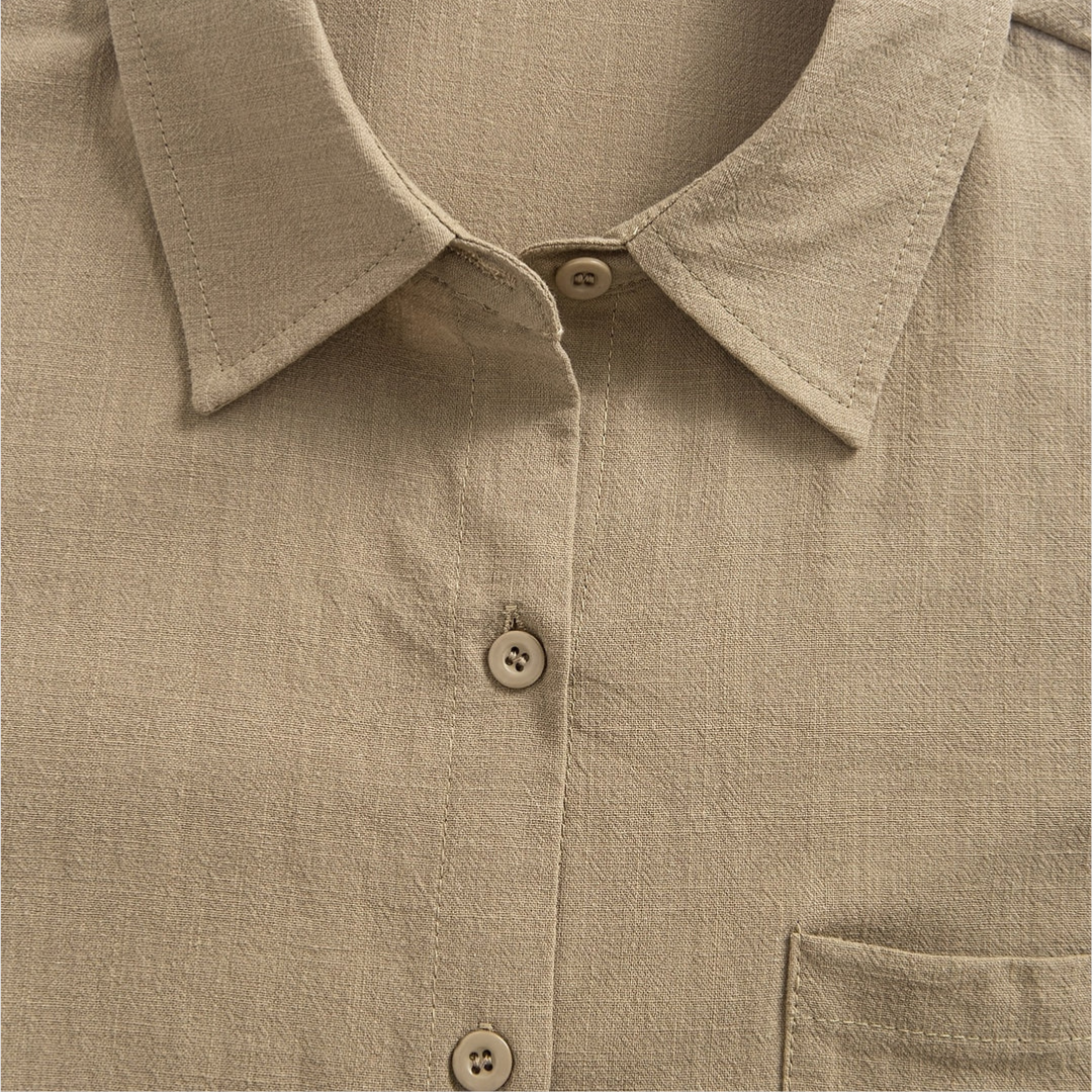 Close-up of the collar and upper button area of a beige soft blouse, highlighting the texture.