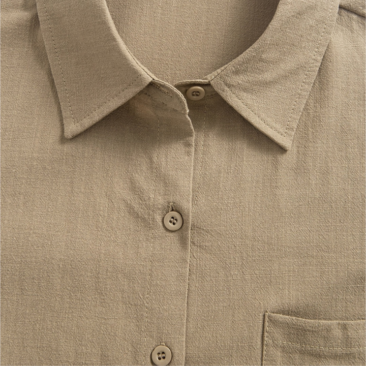 Close-up of the collar and upper button area of a beige soft blouse, highlighting the texture.