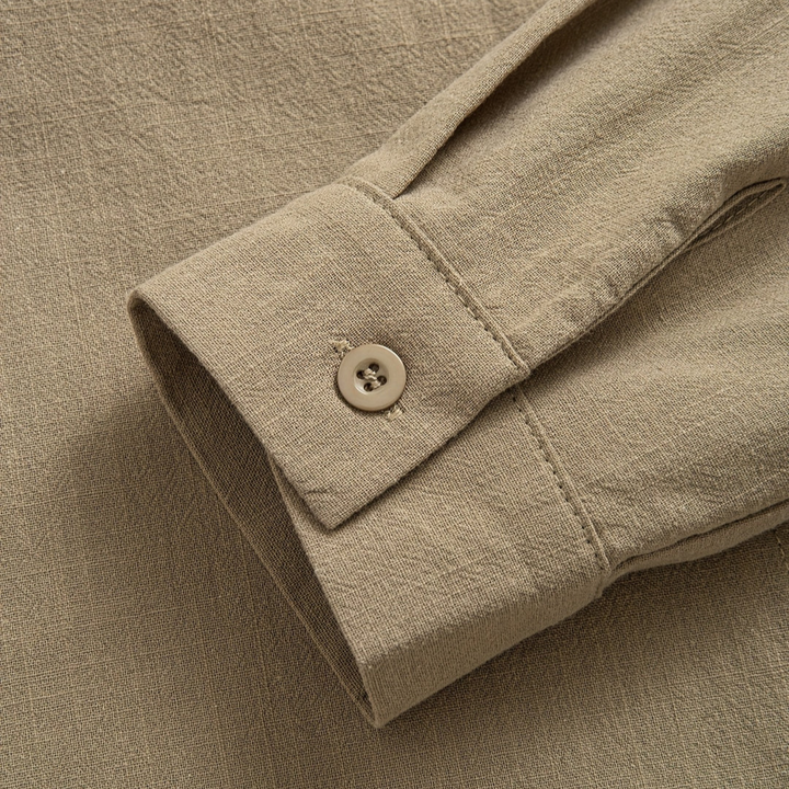 Detailed view of a beige blouse sleeve with buttoned cuff, showcasing texture and craftsmanship.