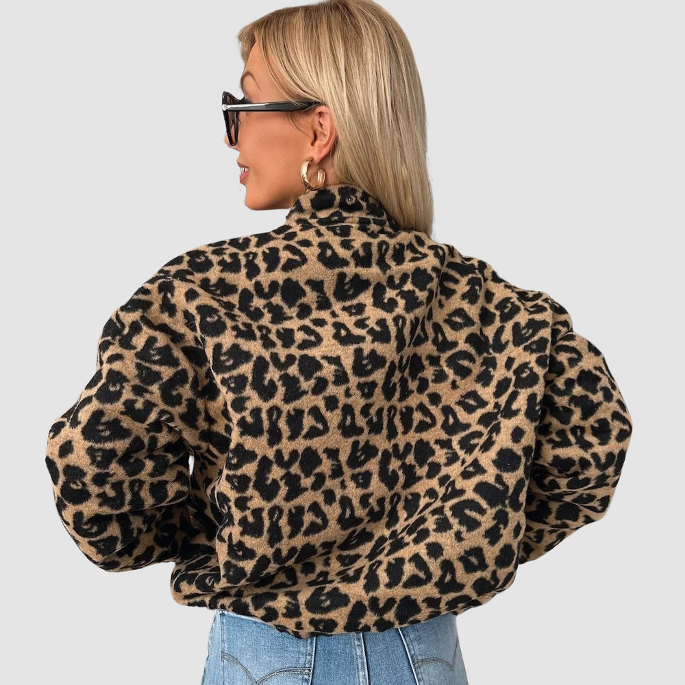 Back view of woman in leopard print jacket and blue jeans, light background.