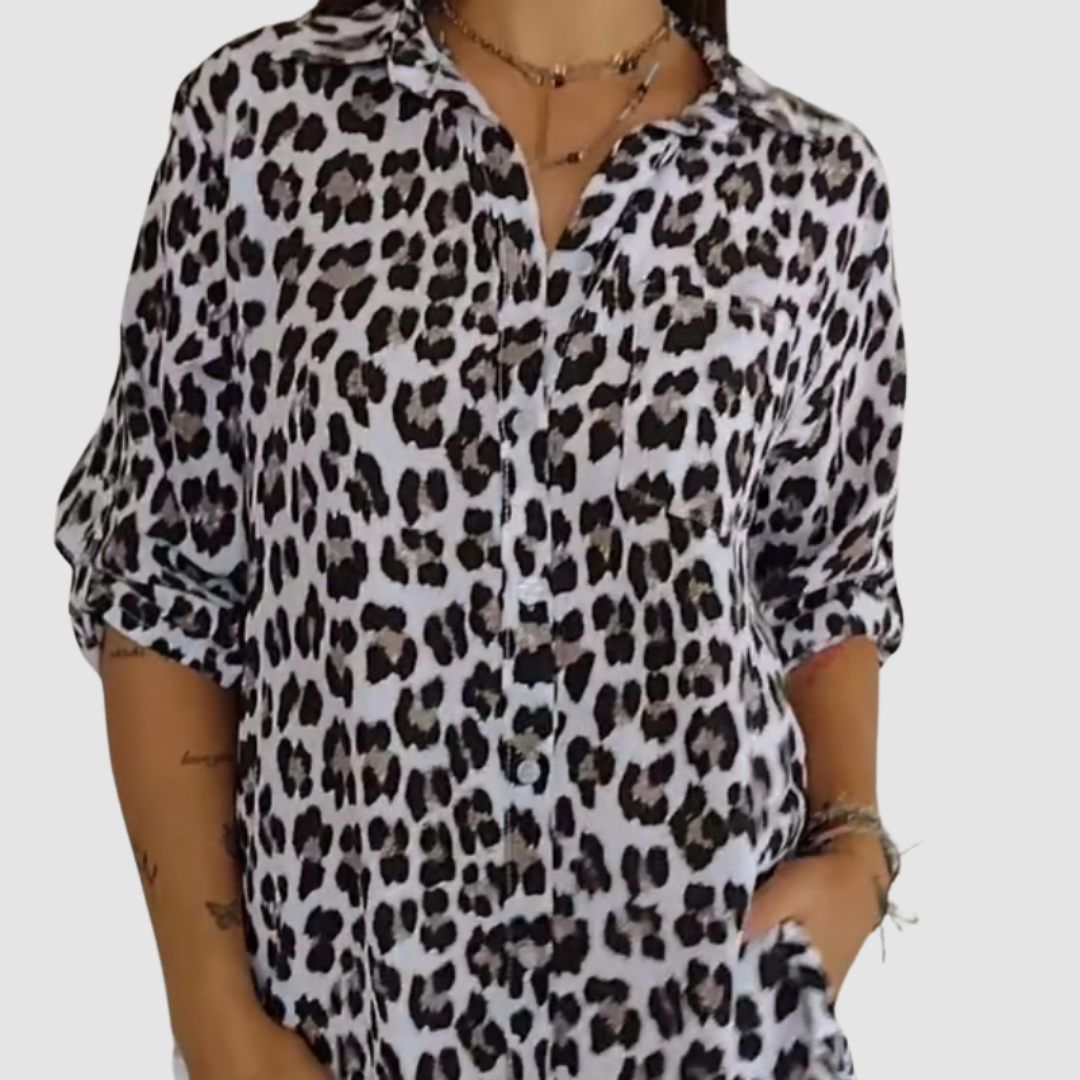 Close-up of a woman wearing a white leopard print blouse with rolled sleeves. Studio background.