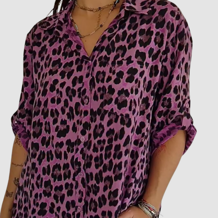 Woman wearing a purple leopard print blouse with rolled sleeves. Studio background.