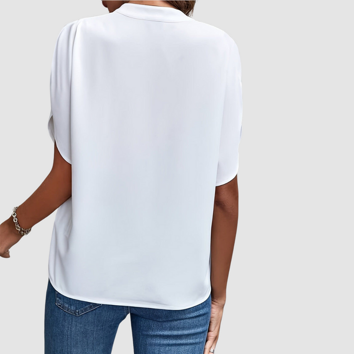 Back view of a white draped blouse, showcasing smooth, flowing fabric and easy fit, paired with blue jeans, studio setting.