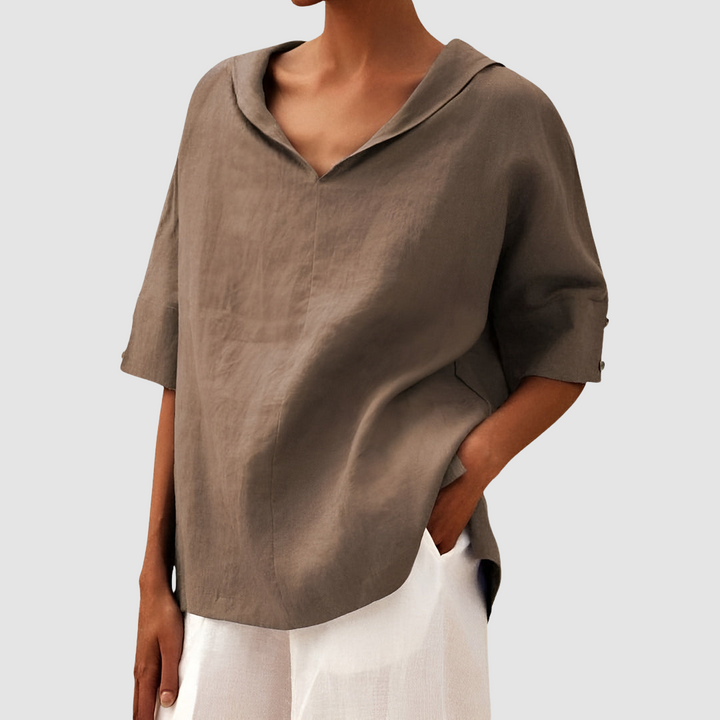 Beige blouse with a V-neck and short sleeves, matched with white pants, studio environment.