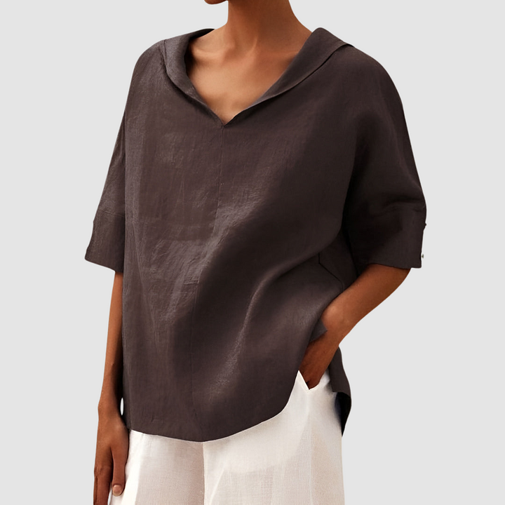 Dark brown blouse with V-neck and short sleeves, paired with white pants, studio setting.