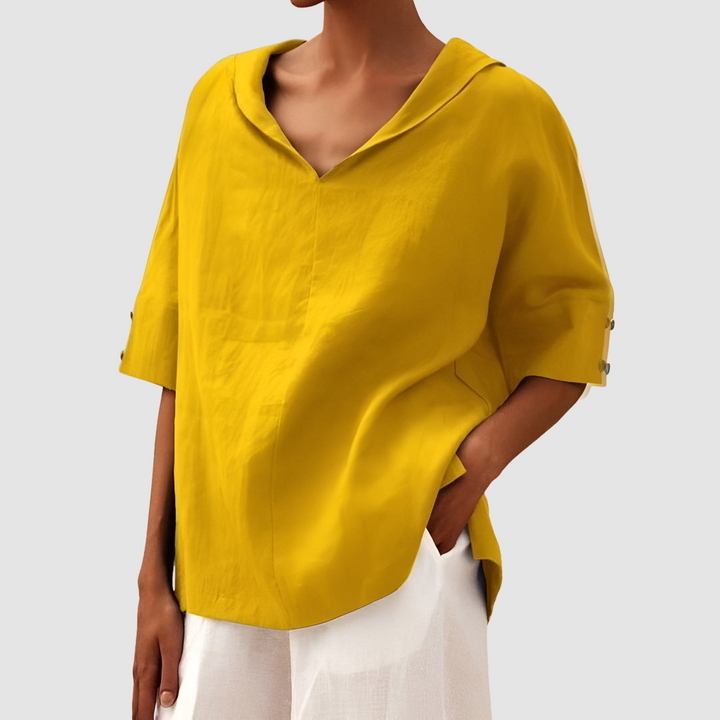 Vibrant yellow blouse with V-neck and short sleeves, worn alongside white pants, studio background.