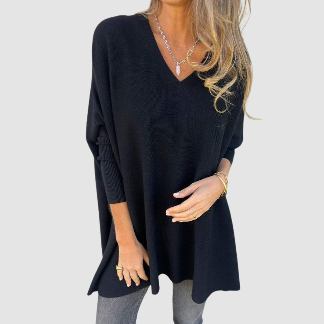 Black v-neck sweater with long sleeves, worn by model with loose hair and jewelry on a plain background.