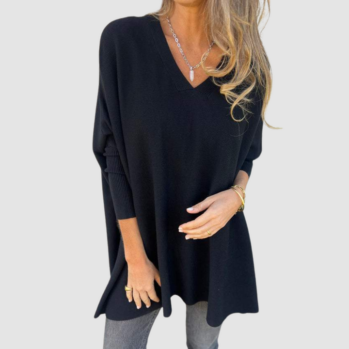 Black v-neck sweater with long sleeves, worn by model with loose hair and jewelry on a plain background.