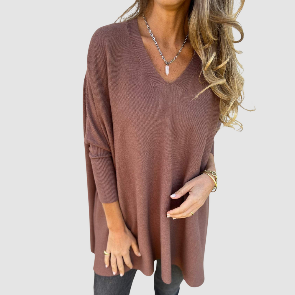 Brown v-neck sweater with long sleeves, worn by model with loose hair and jewelry on a plain background.