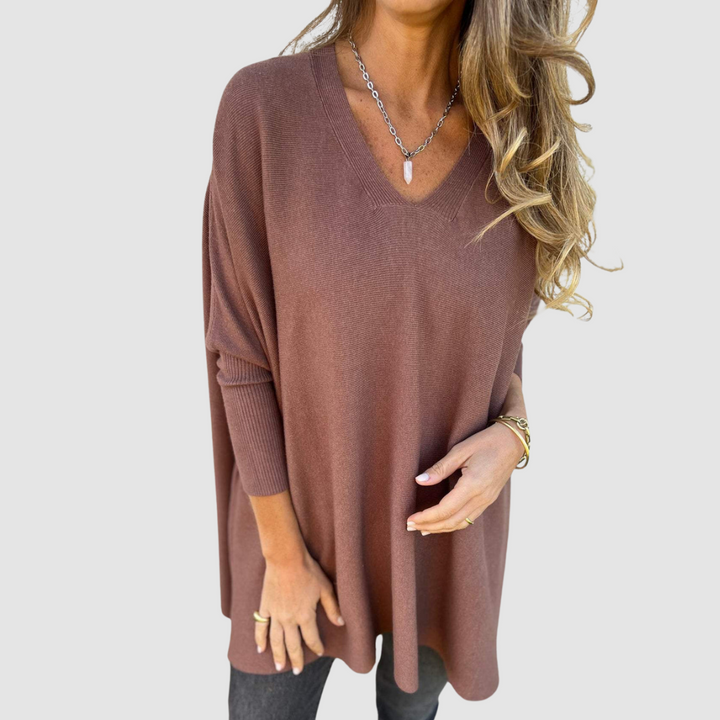Brown v-neck sweater with long sleeves, worn by model with loose hair and jewelry on a plain background.