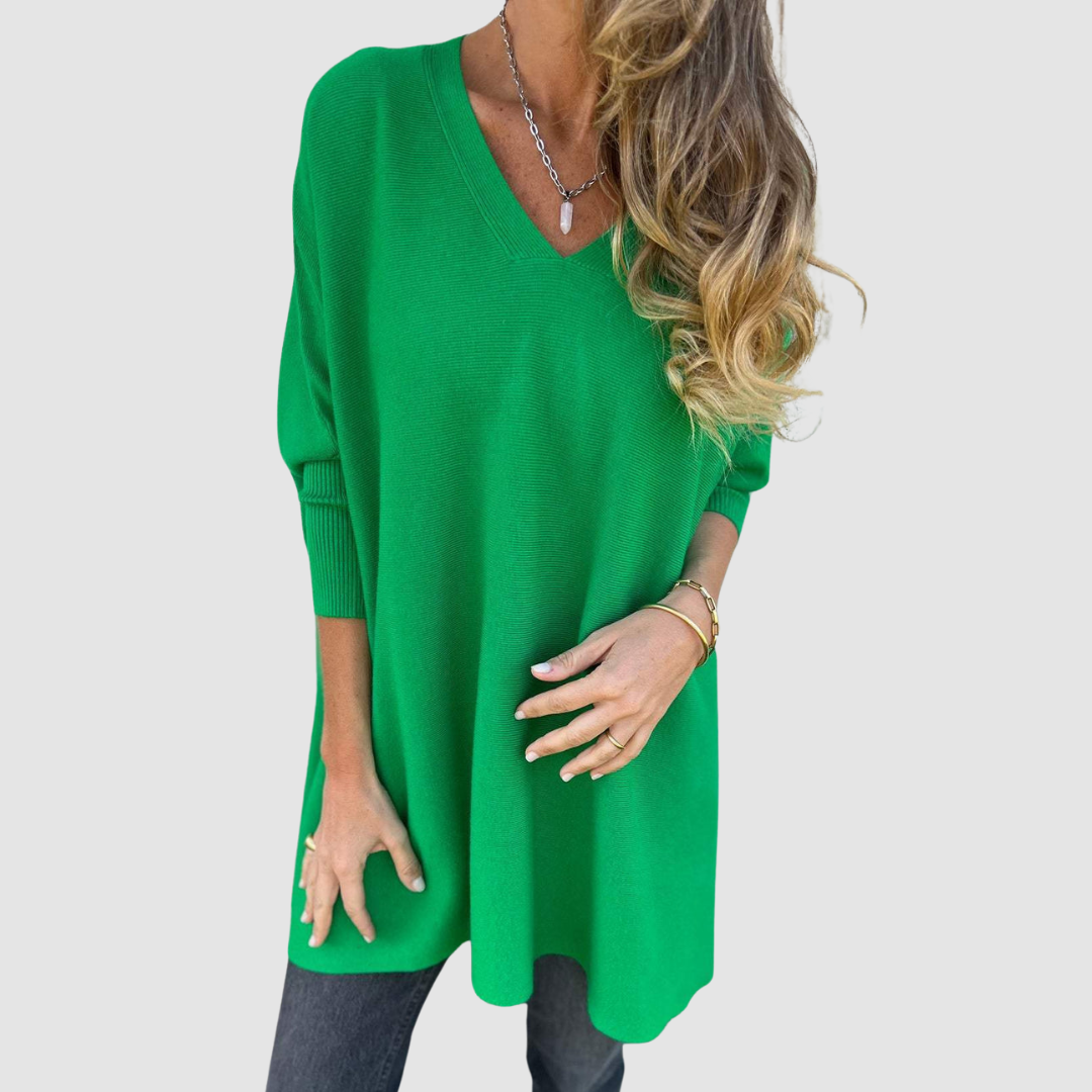 Green v-neck sweater with long sleeves, worn by model with loose hair and jewelry on a plain background.