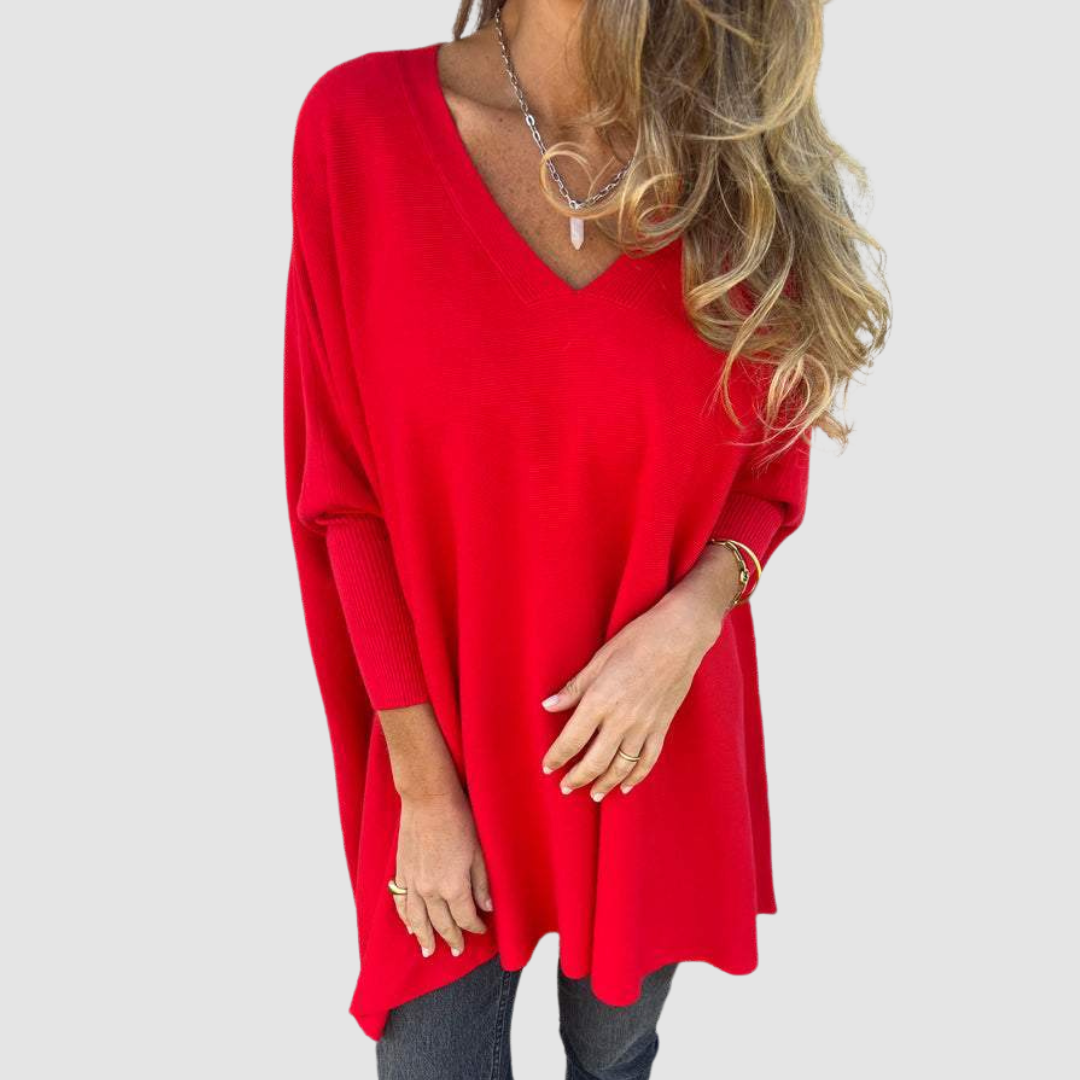 Red v-neck sweater with long sleeves, worn by model with loose hair and jewelry on a plain background.