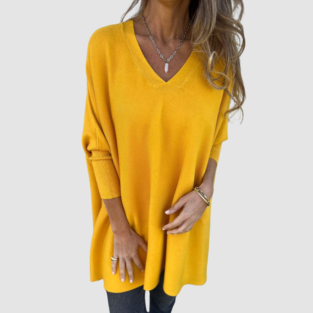 Yellow v-neck sweater with long sleeves, worn by model with loose hair and jewelry on a plain background.