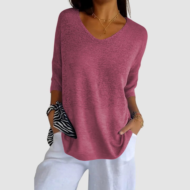 Pink knit V-neck top with short sleeves, paired with white pants. Model&