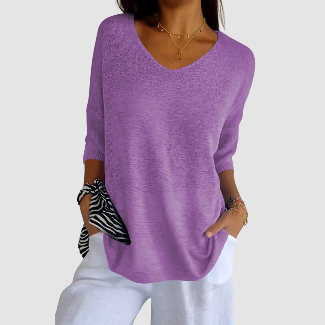 Purple knit V-neck top with short sleeves, paired with white pants. Model&