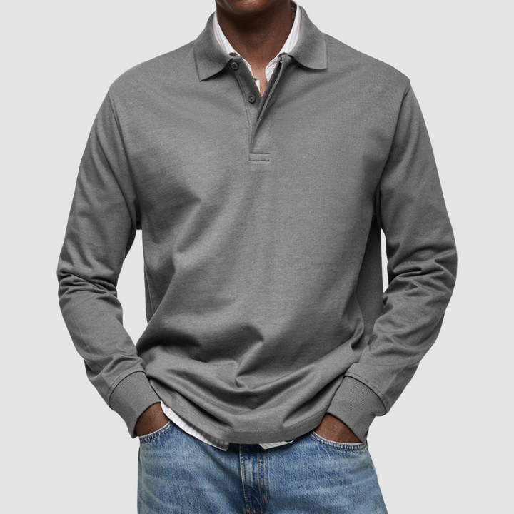 Gray long sleeve polo shirt with button collar, worn over striped shirt, paired with jeans; studio setting.