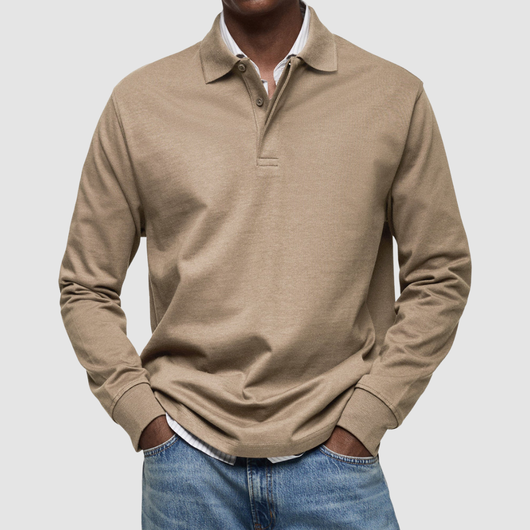 Beige long sleeve polo shirt with button collar, worn over striped shirt, paired with jeans; studio setting.