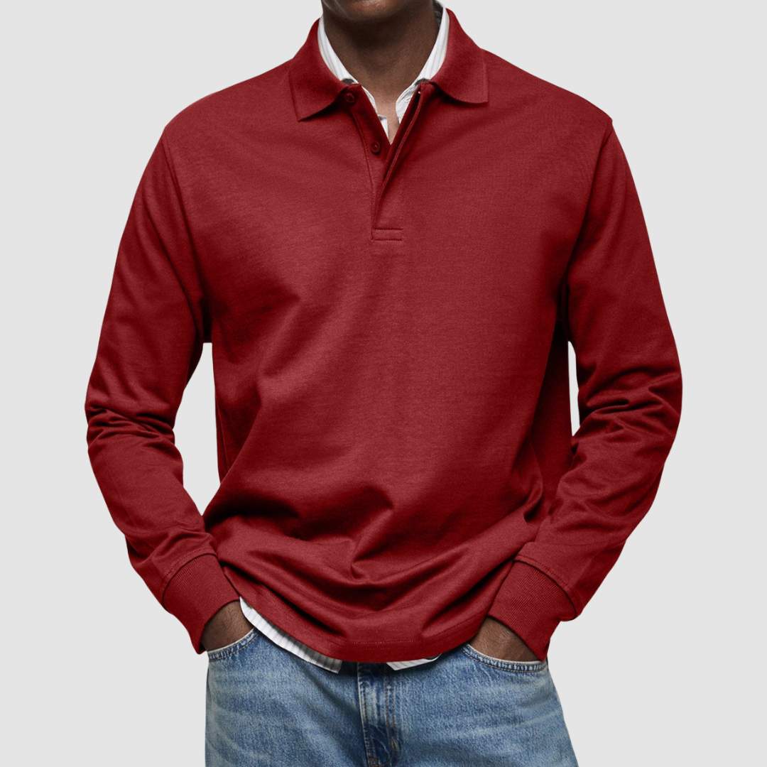 Red long sleeve polo shirt with button collar, worn over striped shirt, paired with jeans; studio setting.