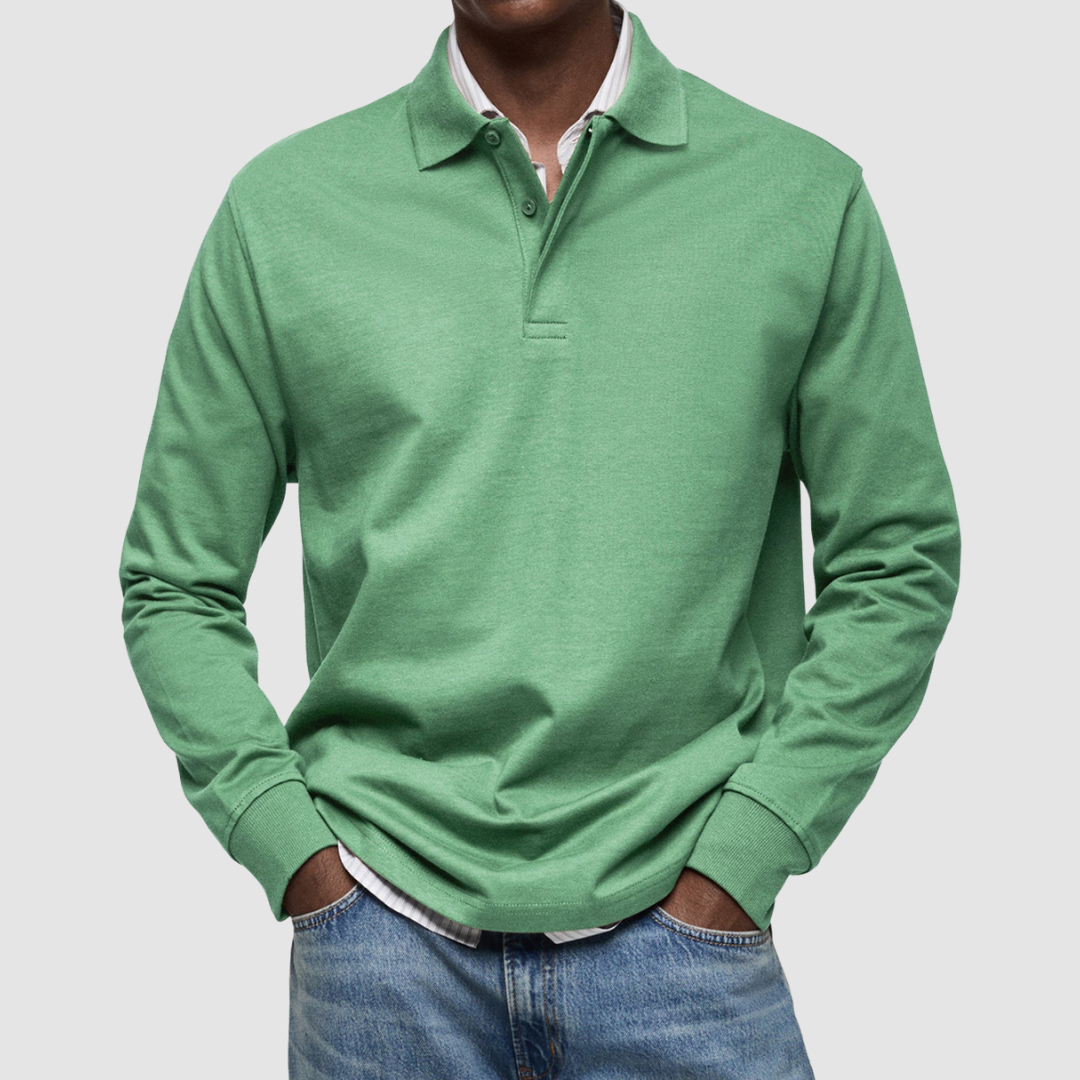 Green long sleeve polo shirt with button collar, worn over striped shirt, paired with jeans; studio setting.