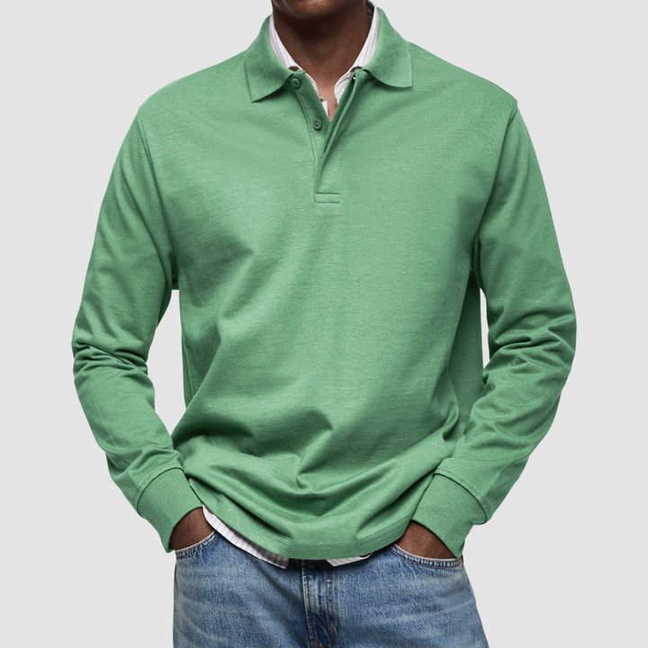 Green long sleeve polo shirt with button collar, worn over striped shirt, paired with jeans; studio setting.
