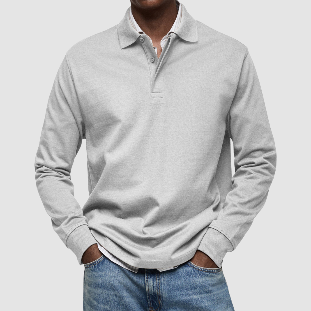 Light gray long sleeve polo shirt with button collar, worn over striped shirt, paired with jeans; studio setting.