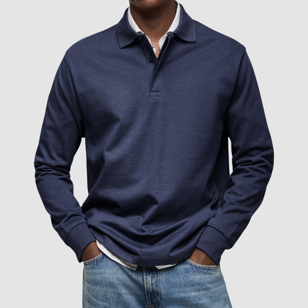 Navy long sleeve polo shirt with button collar, worn over striped shirt, paired with jeans; studio setting.