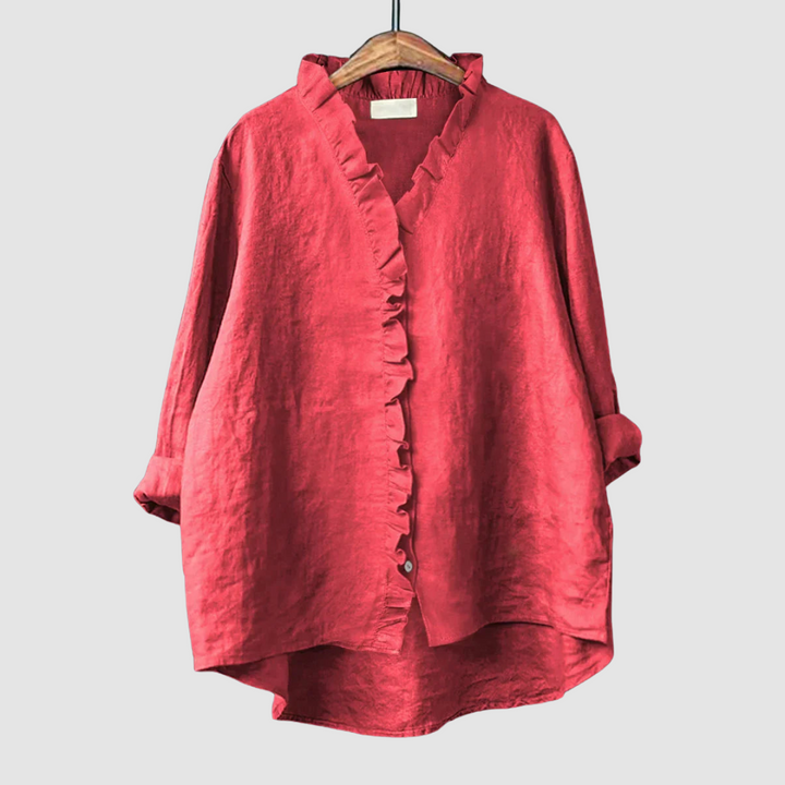 Rich red blouse with ruffled collar and button closure on wooden hanger, set against a light gray background.