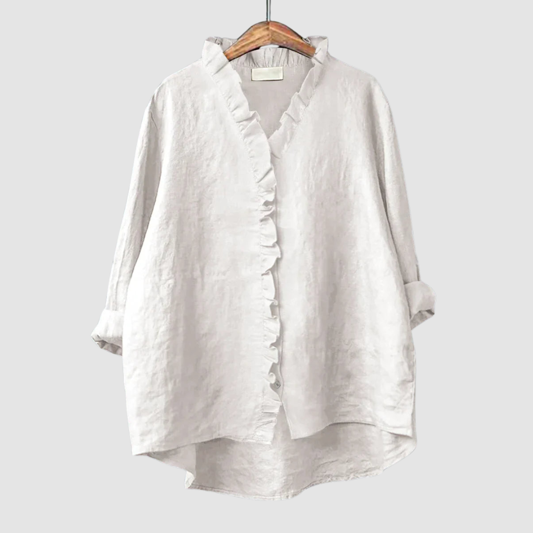Light white blouse with ruffled collar and button closure on wooden hanger, set against a light gray background.